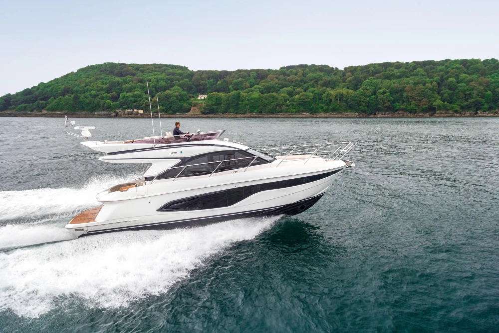 2023 Princess F45 yacht cruising on open water near lush green coastline.