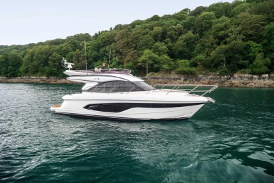 2023 Princess F45 yacht cruising near lush green shoreline.
