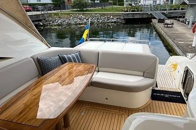 2007 Princess V48 yacht with elegant outdoor seating and wooden table by the water.